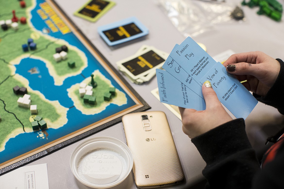 LOREN BENOIT/PressStephanie Billman looks through her event cards while playing &quot;Archaic Realm Missionaries&quot; Monday at Silver Lake Mall. Event cards, some minor and major, help shape a player's strategy.