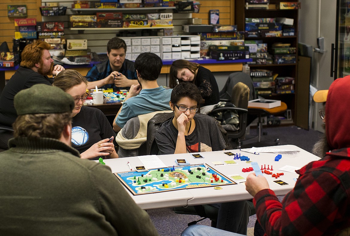 LOREN BENOIT/PressVanessa Bastida, center, ponders her strategy before her turn while playing &quot;Archaic Realm Missionaries&quot; Monday in Strategy and Games at the Silver Lake Mall.