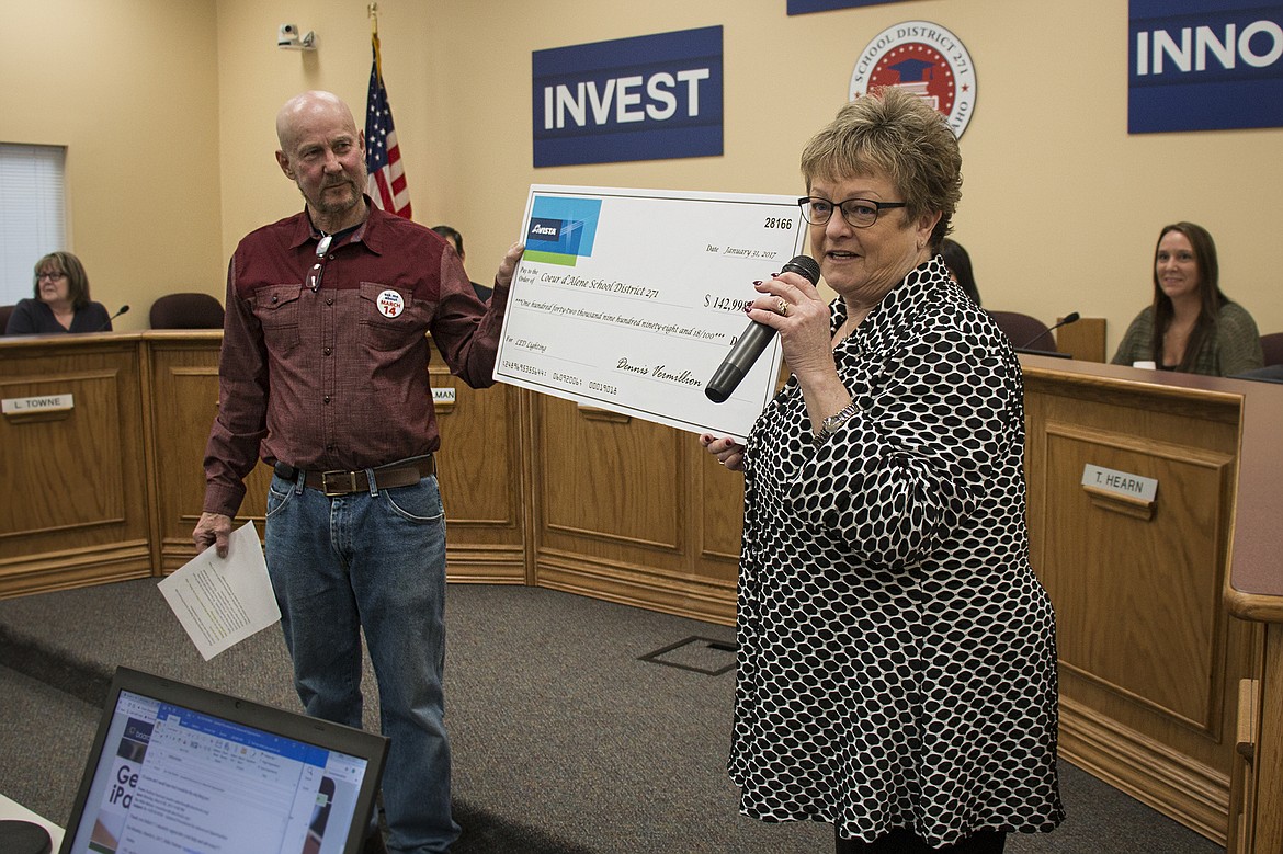 BETHANY BLITZ/PressCoeur d&#146;Alene School Board Trustee Dave Eubanks accepts a check on behalf of the school district from Sharmon Schmitt, an account executive at Avista, for $142,998 in energy efficiency rebates and incentives for 2016. Schmitt said that actually, the check should be for over $150,000 and that she&#146;d get one for the correct amount to the district next week.