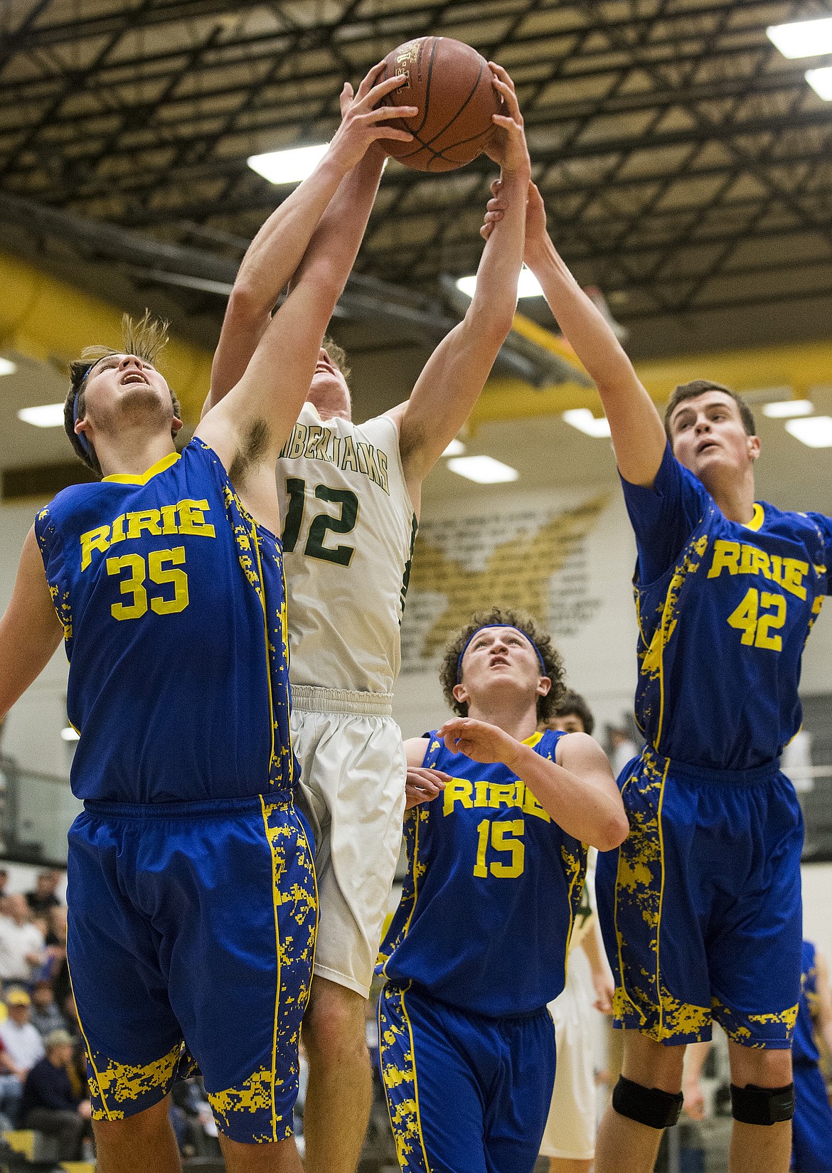 LOREN BENOIT/PressKiefer Gibson (12), of St. Maries, gathers an offensive rebound but is swarmed by Ririe defenders Matthew Johnson (35), Jace Johnson (15) and Michael Ure (42)  during Friday's 5A state semifinal game at Capital High School.