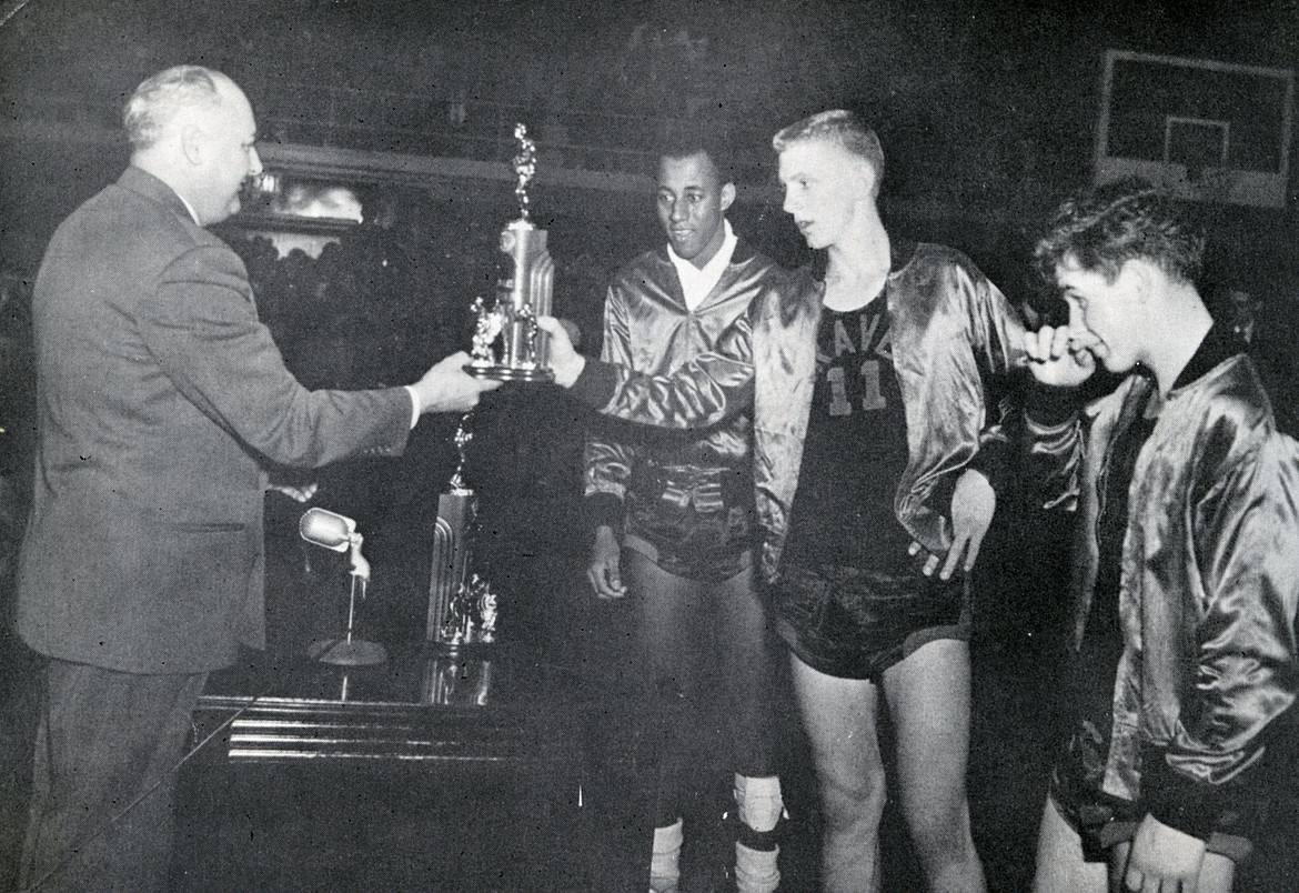 Jerry Siderius (11) accepts the second-place trophy for the Flathead Braves at the Northern Division tourney in 1953. The tourney was hosted by Flathead. Rudolph &#147;Zip&#148; Rhoades looks on from behind Siderius, while teammate Frank Landon is at right. (Courtesy Jerry Siderius/1953 high school annual)