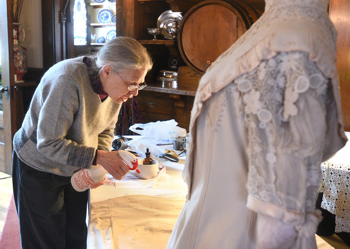 Teresa Knutson cleans a dress damaged from water at the Conrad Mansion. The dress is believed to be Alica Conrad&#146;s from around 1906. (Aaric Bryan/Daily Inter Lake)