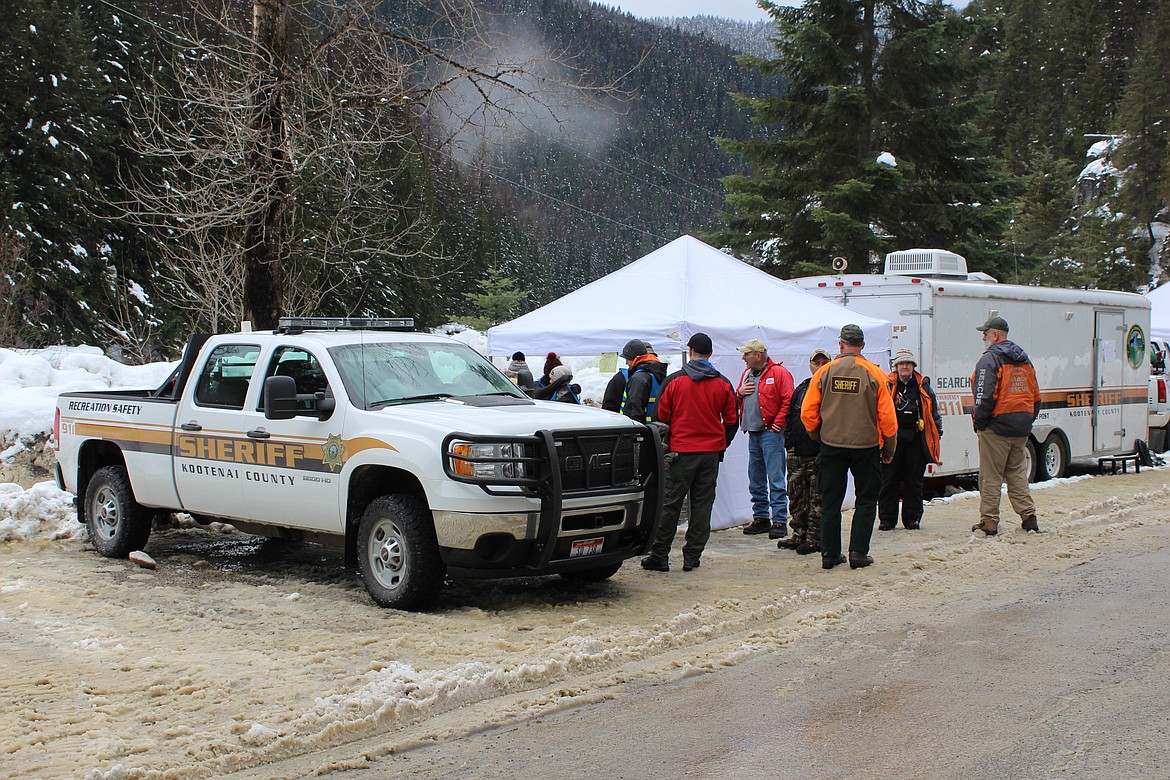 Photo by Chanse Watson 
Search and Rescue crews at their base camp near lost creek gather around to hear the news that Deming had been found.