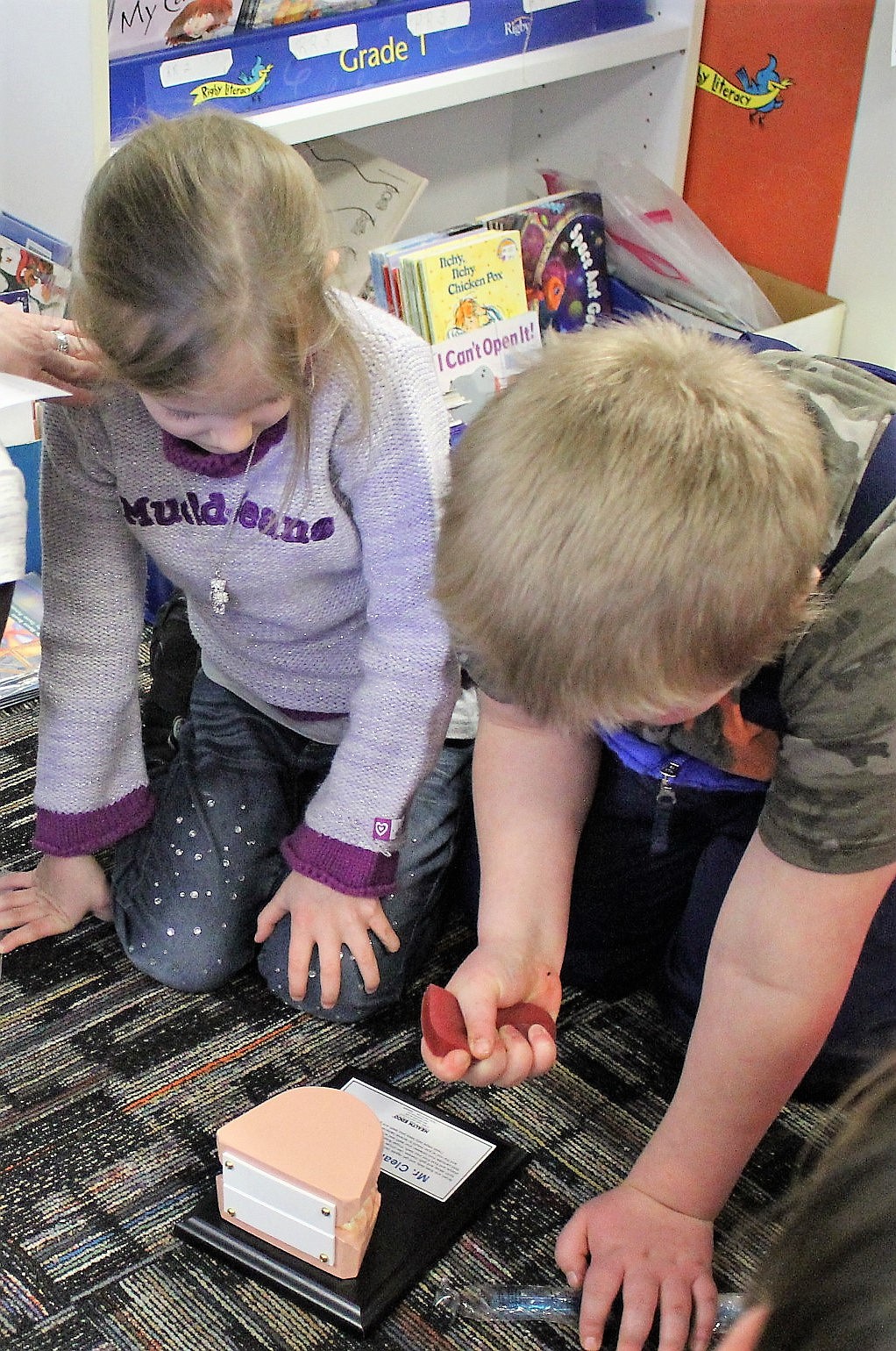 Superior first-graders Laney and Mac examine a rubber tongue and a set of teeth used to show proper brushing techniques during a presentation by school nurse Barb Jasper. (Kathleen Woodford/Mineral Independent).