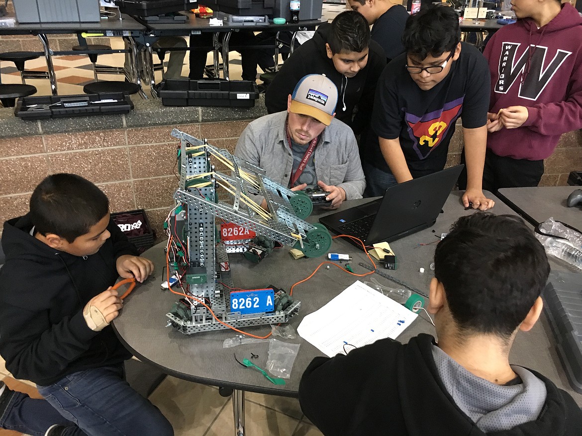 Ted Escobar/The Sun Tribune - Coach Adam Fields, gray, helps one of the Wahluke Junior High VEX Robotics teams prepare for the tournament.