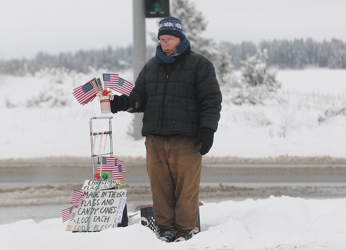 AL WELLENSTEIN, author of &#147;The Life &amp; Times of a Rich Hobo,&#148; stands at Reserve Street and Hutton Ranch Road selling American flags in this file photo. (Aaric Bryan/Daily Inter Lake)