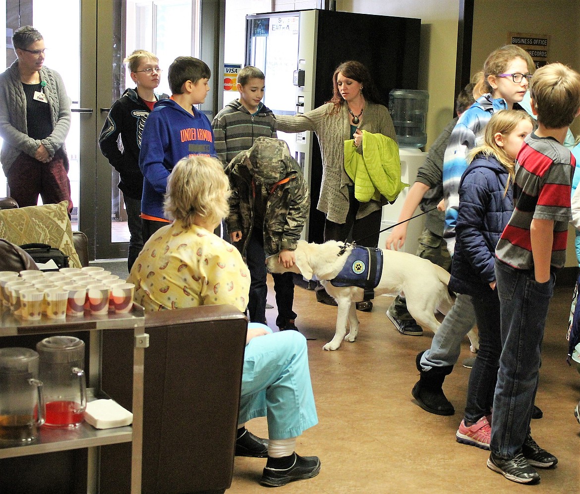 Therapy dog Storm Trooper greets Alberton students as they unveil their art projects in the Mineral Community Hospital (Kathleen Woodford/Mineral Independent).