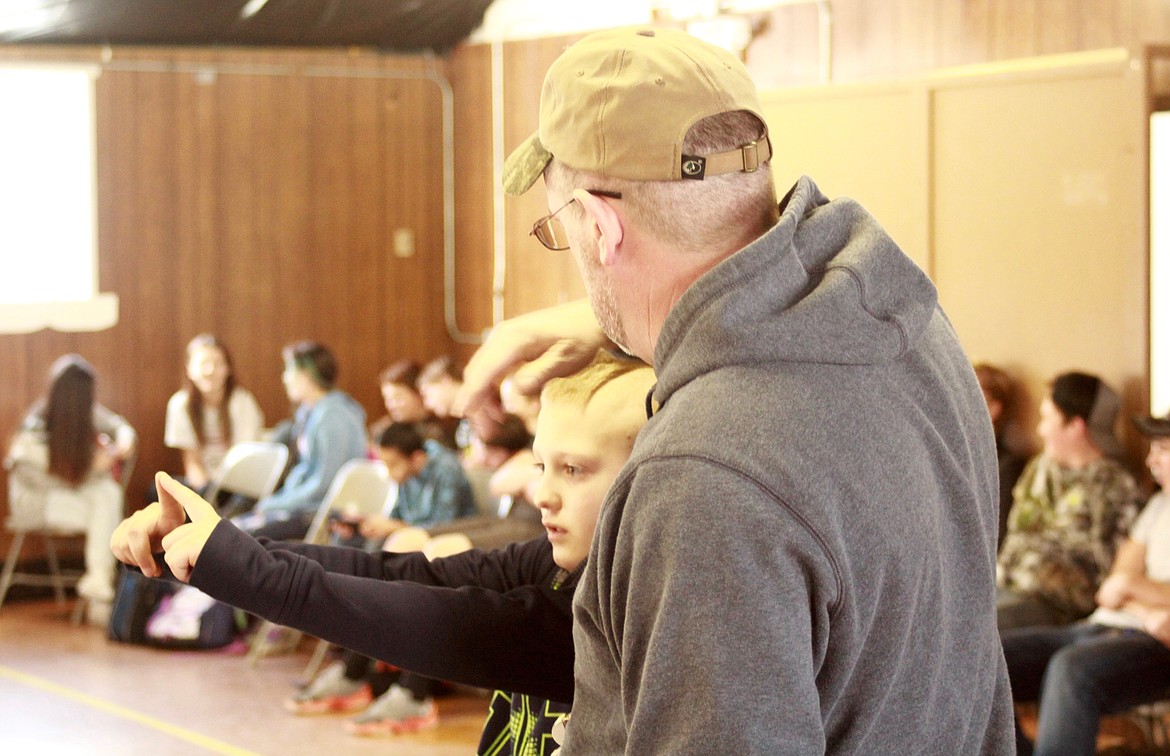 Chris McGuigan gives instructions on how to sight the bow to Jamyson Leetimm during the Archery after school program.