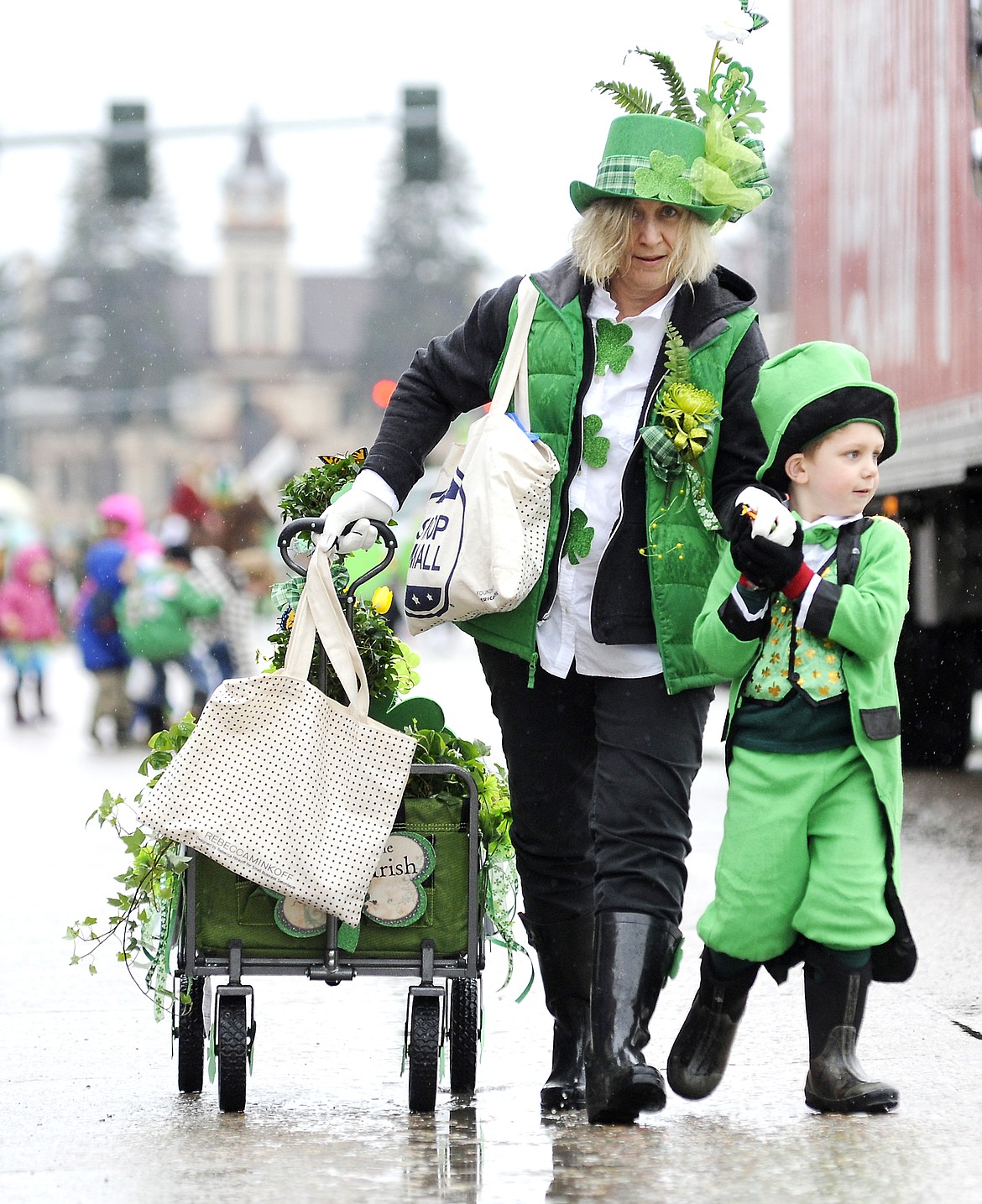 Max Young, top, holds up flowers as he walks with the Rose Mountain Floral participants. Nicholas Walsh, bottom, grabs a handful of candy from his grandma Janet Walsh of the Rose Mountain Floral group in a previous St. Patrick&#146;s Day Parade in Kalispell. (Aaric Bryan/This Week in the Flathead file photo)