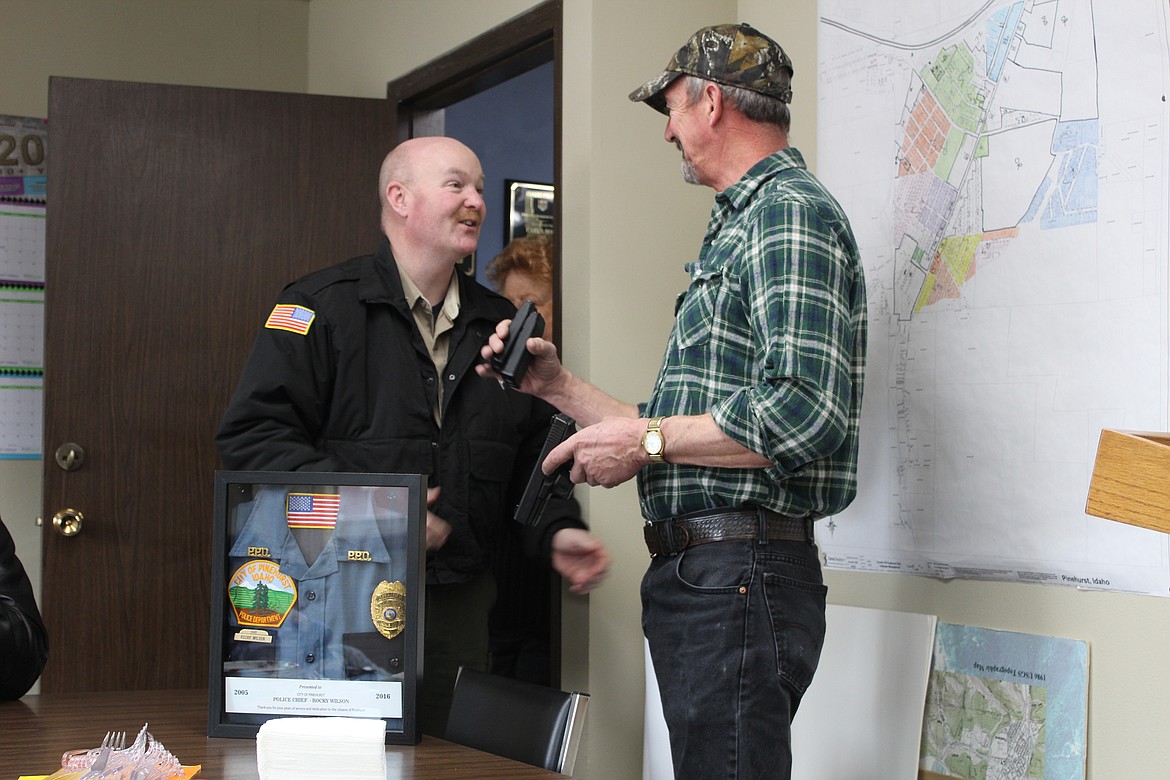 Shoshone County Sheriff Mike Gunderson presents Wilson with his service pistol.