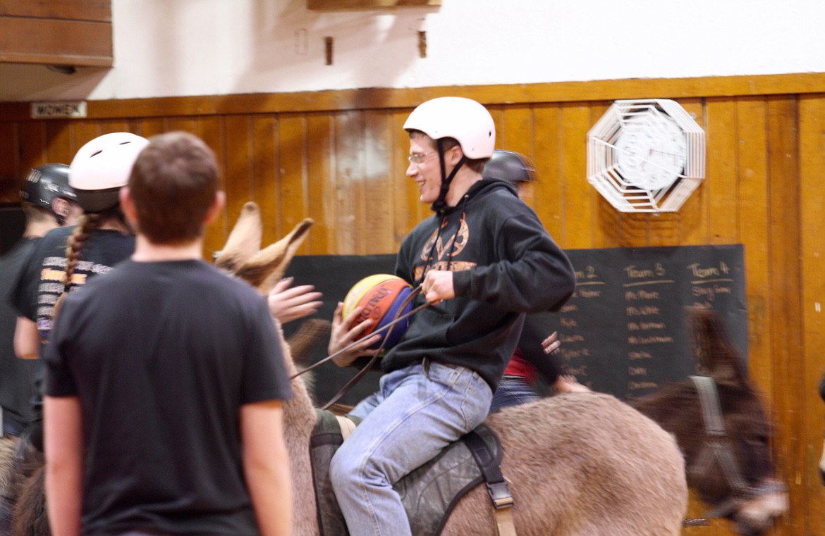 James DeTienne, in the white helmet with the basketball is working a donkey in the old gym during the Hot Springs senior class fundraiser on Friday night, March 10.