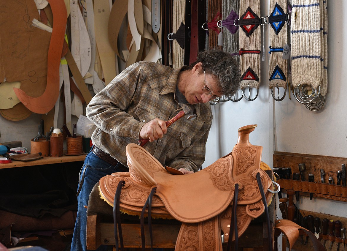 Jeff Morrow works the leather on the 3-B Visalia slick fork saddle. (Aaric Bryan/Daily Inter Lake)