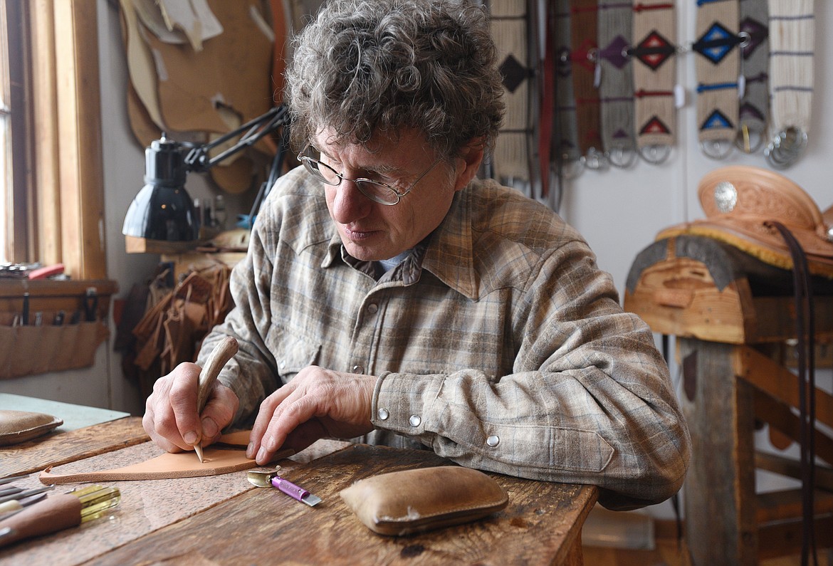 Jeff Morrow carves a flower into a piece of leather at his shop in Nirada. (Aaric Bryan/Daily Inter Lake)