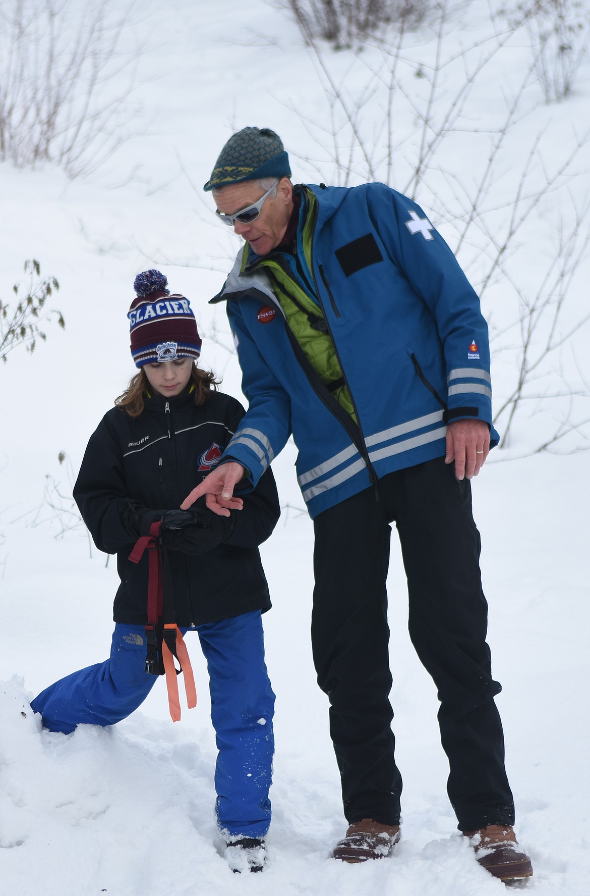 Reid Pickert and Tim Strand use a transceiver to find another avalanche beacon in the snow.