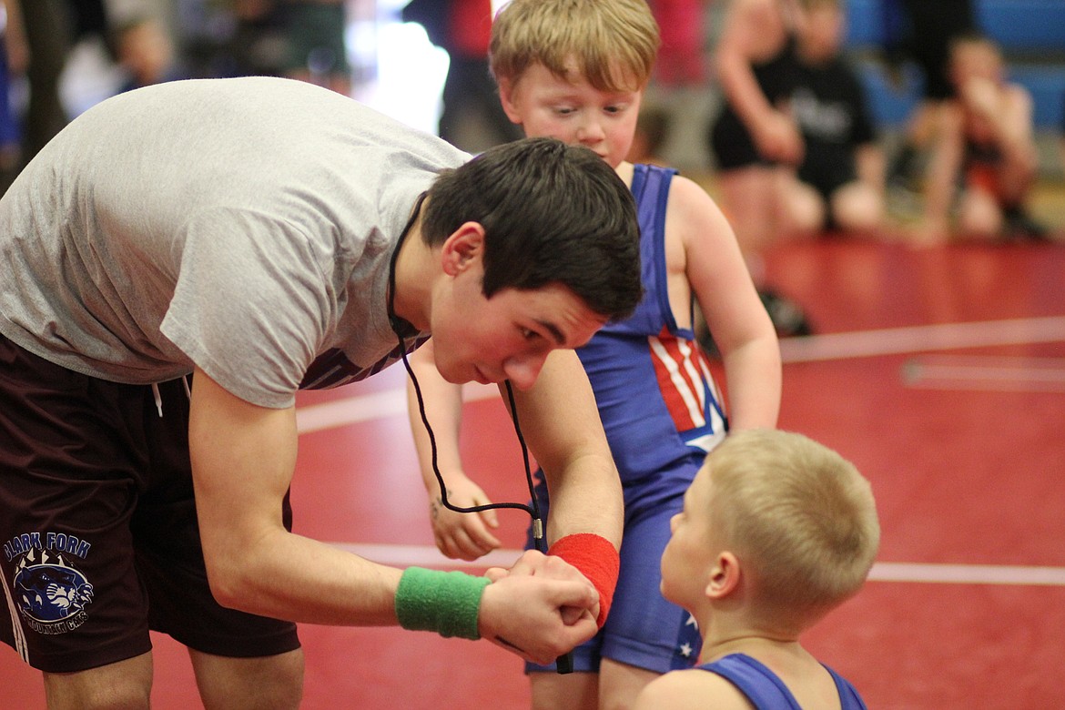 Superior wrestler Kaleb Ververis was a referee at the Little Guy Wrestling Tournament in Superior on Saturday. He explains a technique to Clark Fork beginner Chris Wood. Wood was matched up against Evan Fehlings. Fehlings went on to win the match.