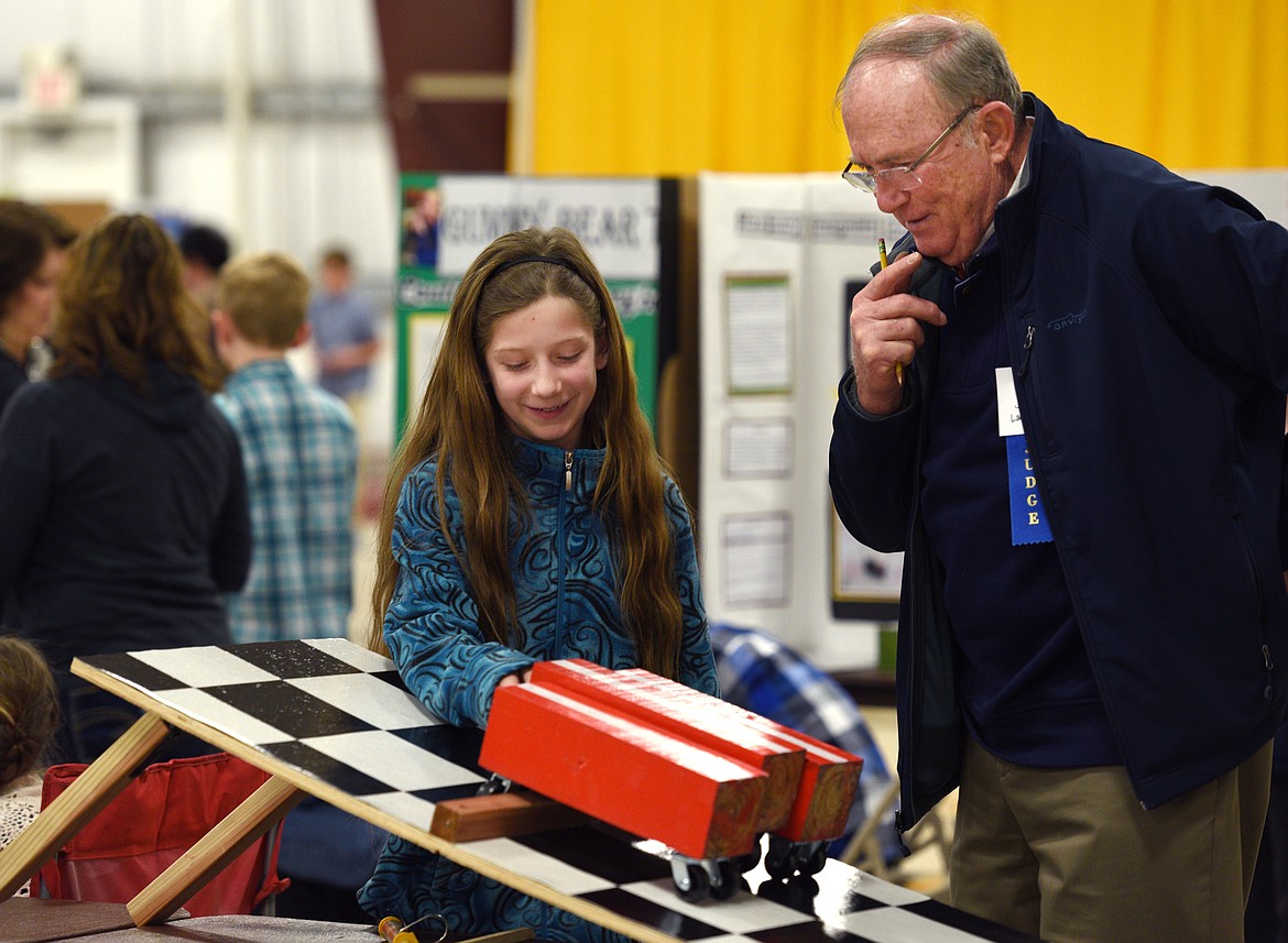 Helena Flats sixth-grader Jasmine Cartwright explains her science project to judge Jim Lambert at the Flathead County Fair on Thursday. Cartwright tested how the size of the wheel impacts the amount of force it takes to get over an obstacle.