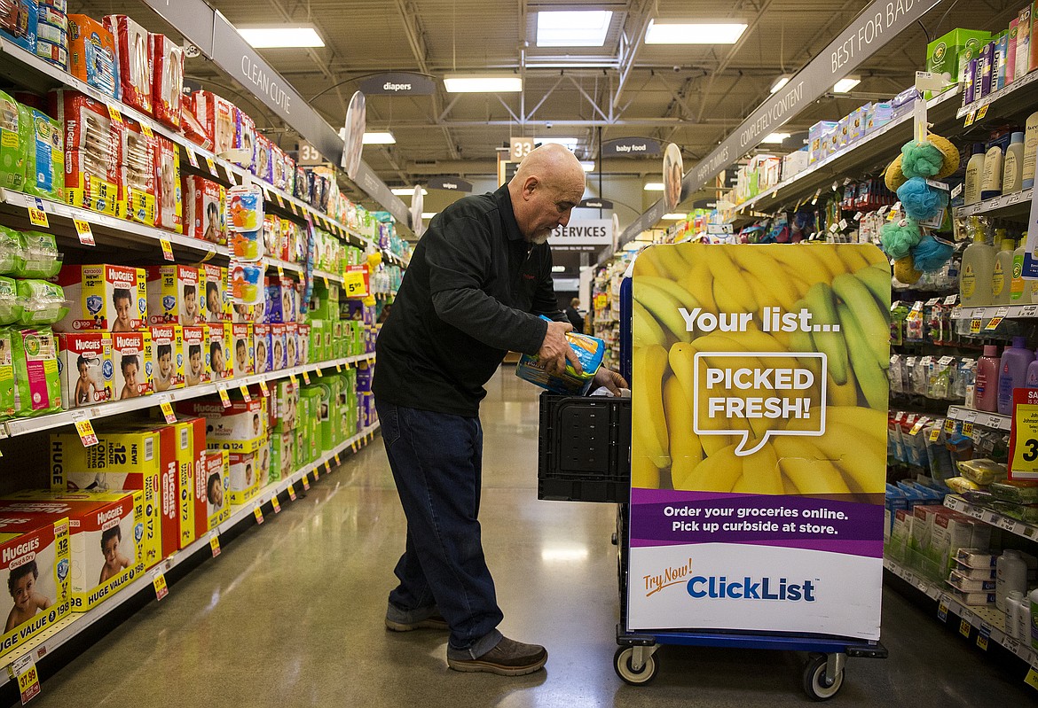 LOREN BENOIT/PressFred Meyer employee Manny Tavison places a diaper bag into a ClickList container Wednesday afternoon. Tavison and other ClickList workers go around the store gathering grocery items for pickup by customers who might not have time to shop in the store.