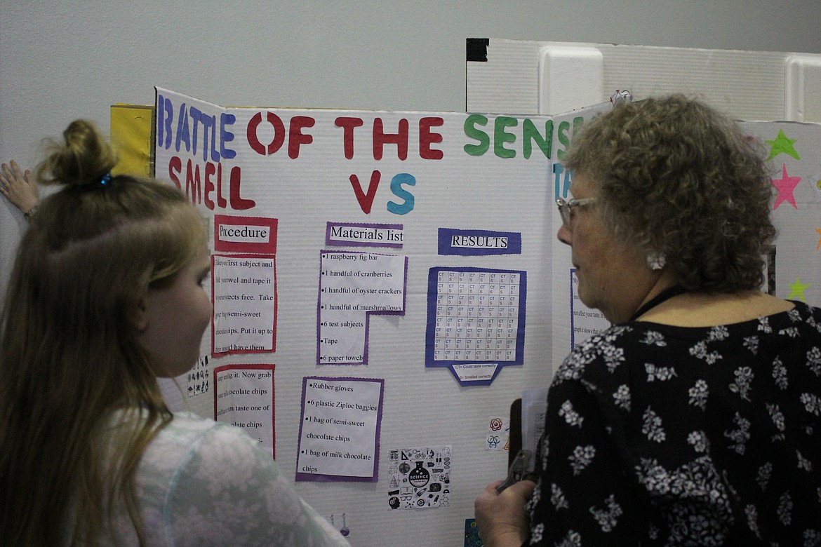 Brooke Filek, grade 5, won silver at the St. Regis science fair for her experiment as to whether smell affects taste. She met with fair organizer and judge, Chris West and explains her conclusion.(Kathleen Woodford/Mineral Independent).