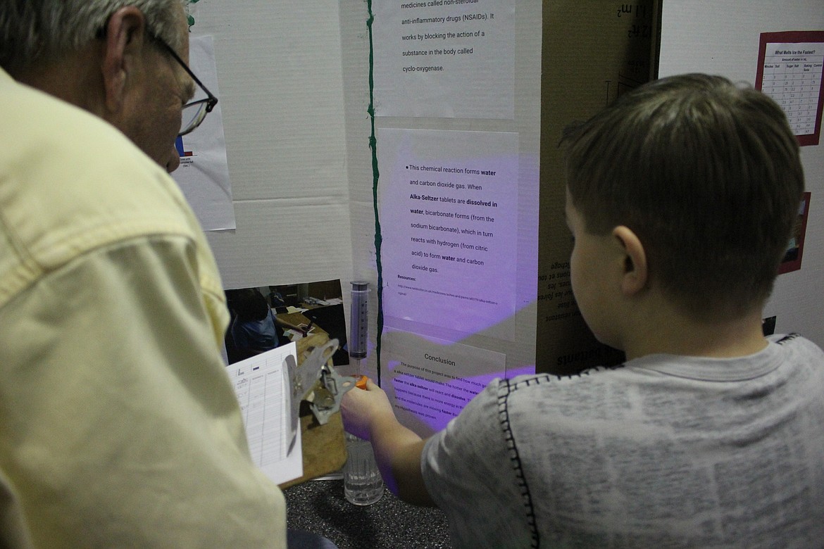 Aaron Stansfield, grade 6, received gold after discovering that if you put a whole tablet of Alka-Seltzer in water then it will produce the most gas. Here he explains his hypothesis to a judge at the March 7 St. Regis science fair. (Kathleen Woodford/Mineral Independent).