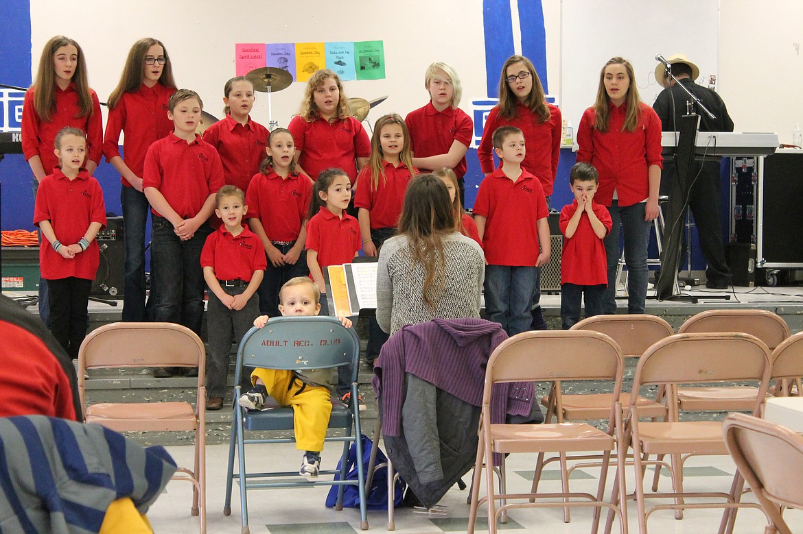 Charles H. Featherstone/Columbia Basin Herald
A little boy looks on, more interested in the audience than the singers, as the children&#146;s choir Voices of a New Day sings at Frontier Middle School as part of the Bagels for Books fundraiser on Saturday.