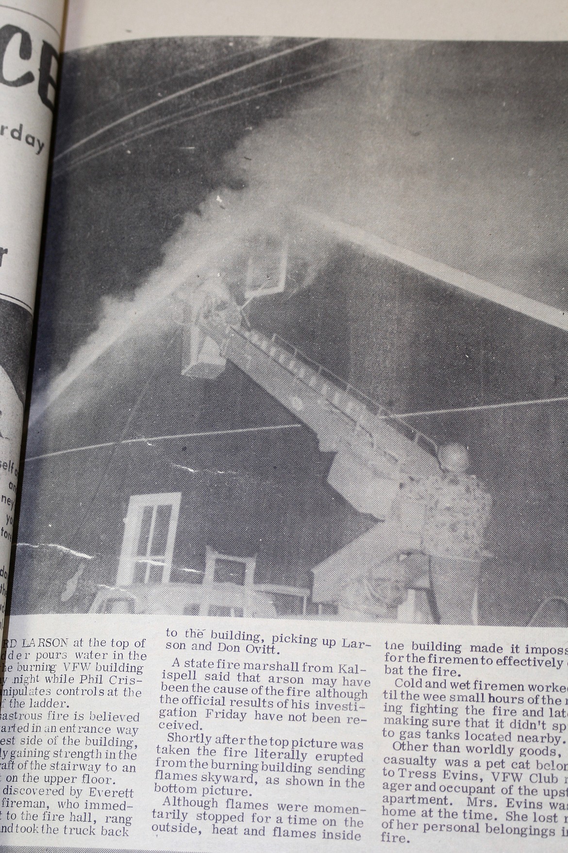 THIS NEWSPAPER clipping shows Leonard Larson at the top of the ladder pouring water inside the VFW. In the lower right of the photo operating the controls is Phil Crismore.