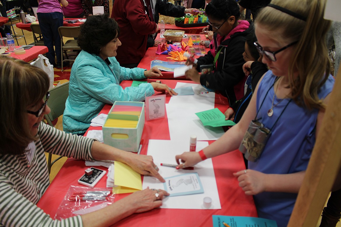 Chanet Stevenson/The Sun Tribune - Reagan Jones participates in one of the children's craft activities offered during during the festival Saturday at Othello High School. Activities included painting projects, origami, mask making, and many more.