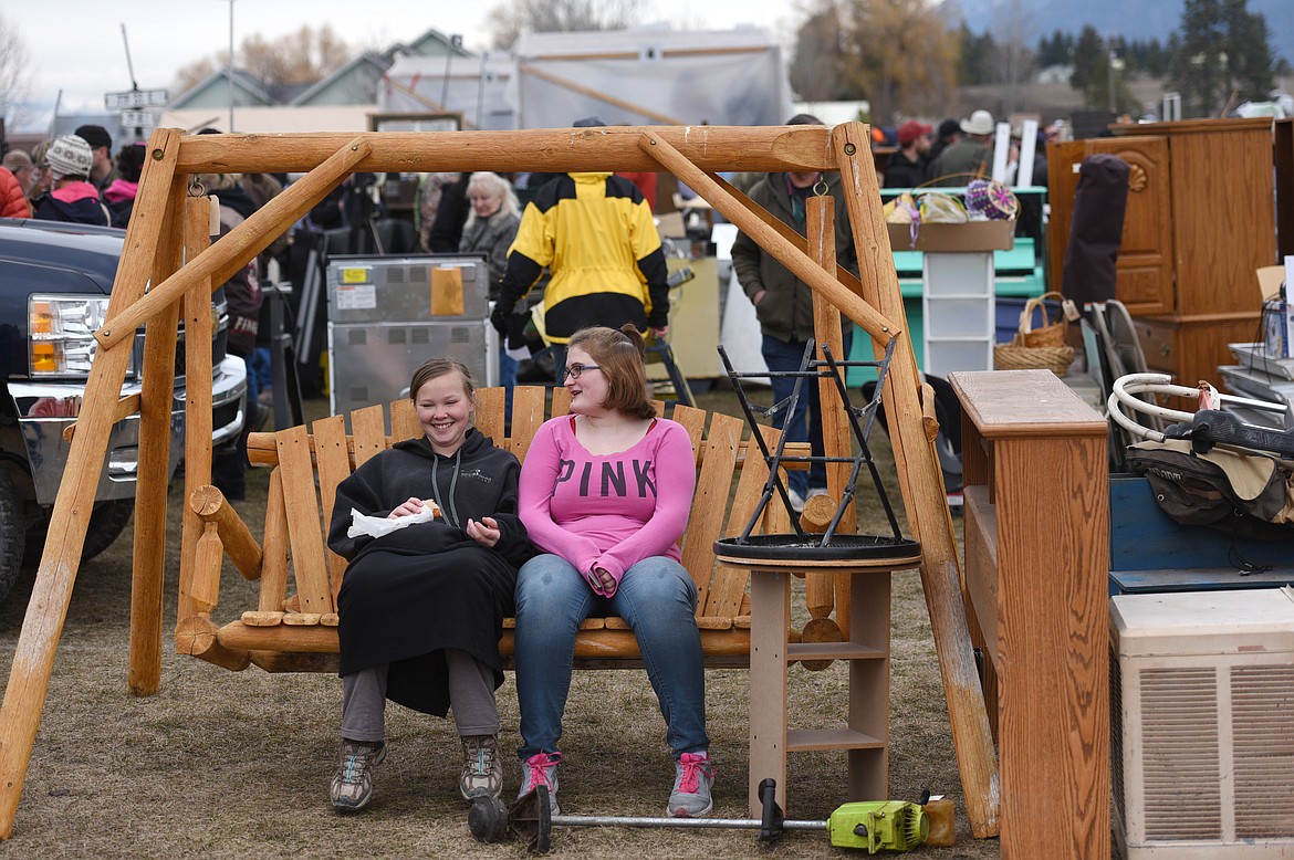 Lisa Miller, left, and Brittney Lockhart rest on a swing during the 51st Creston Auction on Saturday.