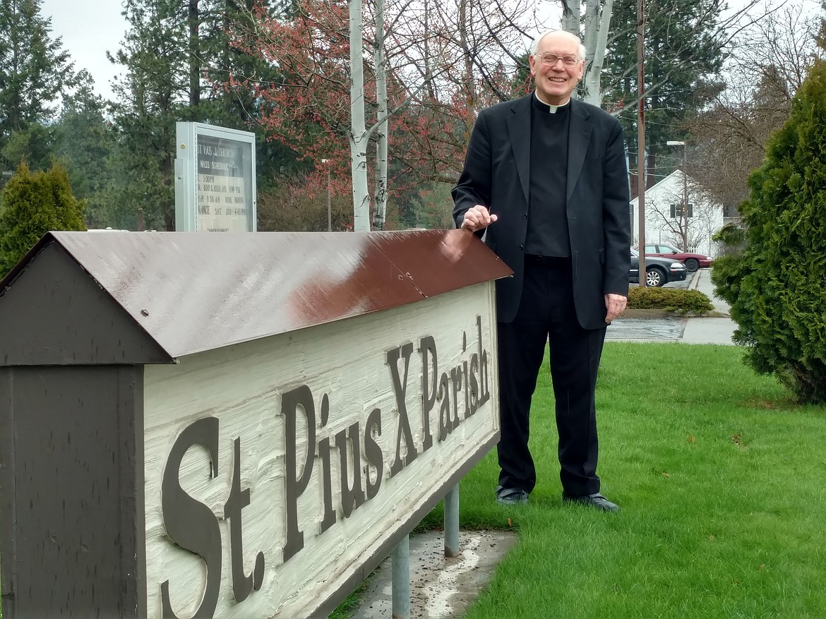 DEVIN HEILMAN/Press
St. Pius X Catholic Church parish priest Father Roger LaChance stands with his church sign during the drizzly morning Wednesday. LaChance is preparing to retire in June, when he will return to his hometown of Pocatello and continue the Lord&#146;s work where he is needed.