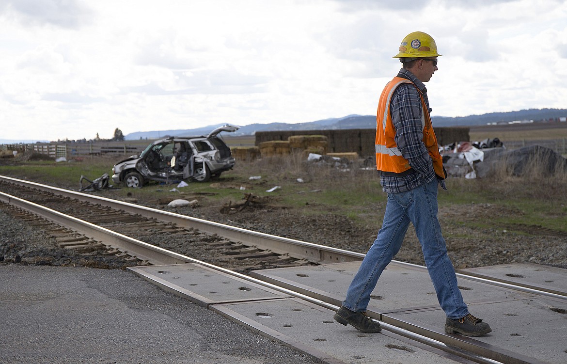 LISA JAMES/Press
A Union Pacific Railroad employee crosses the tracks on Huetter Road near Lancaster Avenue in Rathdrum where a Chevy Trailblazer, seen in the background, collided with a passing train on Thursday afternoon.