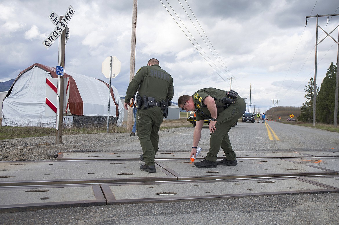 Sgt. Ward Crawford spray paints the tracks at the scene of a collision on Huetter Road near Lancaster Avenue in Rathdrum.