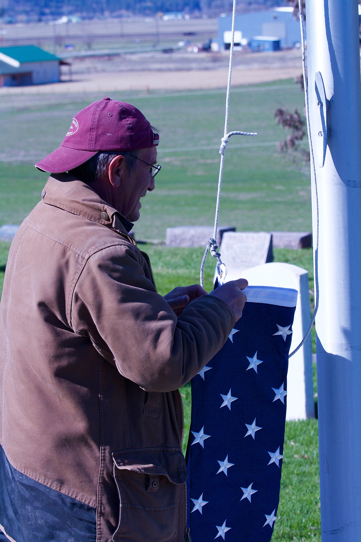 PLAINS CEMETERY sexton Ken Jones works with the American flag to raise it on the rope and flagpole.