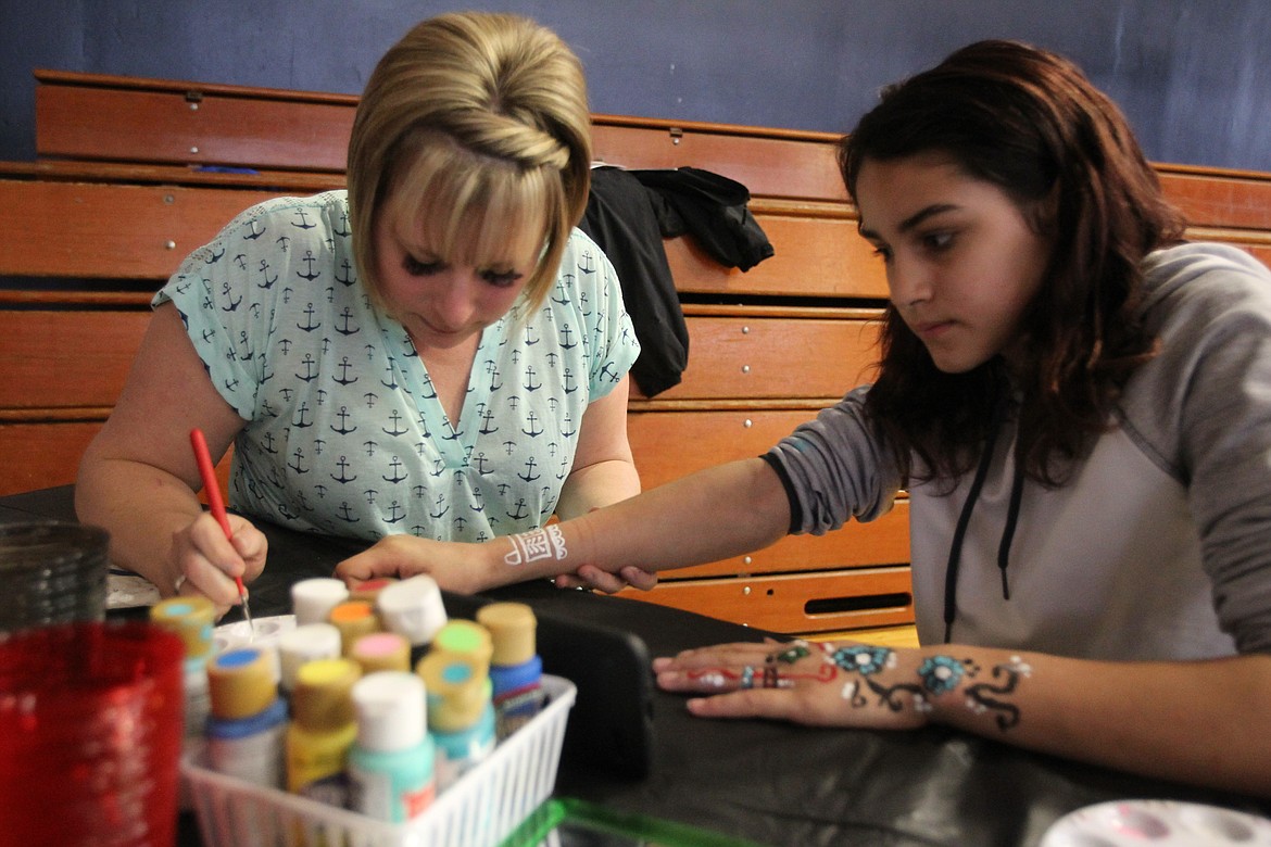 DEVIN HEILMAN/Press
Seventh-grade teacher Amber Miller paints a delicate white henna-style pattern on seventh-grader Annali Dejesus&#146; arm Saturday during the Multicultural Faire in Lakes Magnet Middle School&#146;s gym. Miller explained that henna tattoos are traditional in East India.
