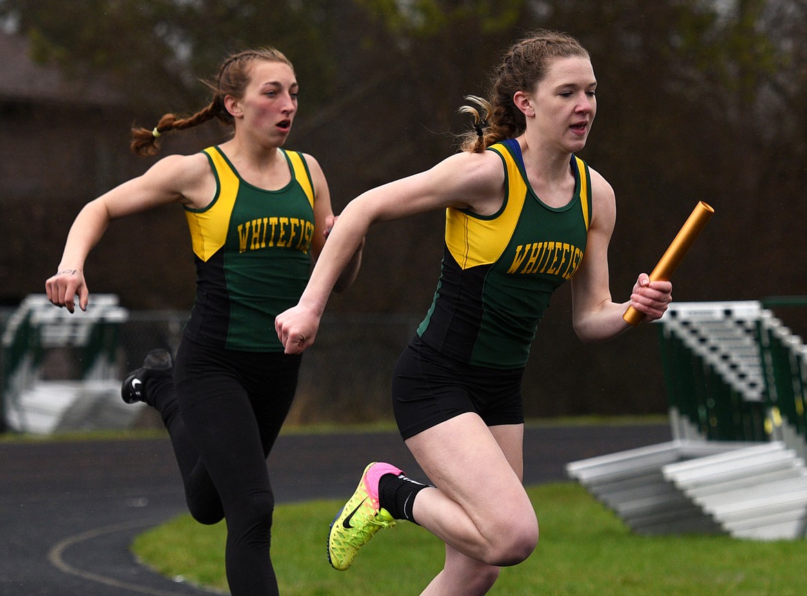 Whitefish's Lauren Schulz takes off with the baton after Alice Wilde handed it off during the final leg of the 4x100-meter relay at the Whitefish ARM Invitational on Saturday. (Aaric Bryan/Daily Inter Lake)