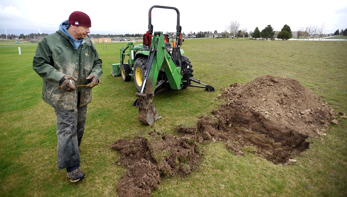 Brodie Morton of the City of Kalispell Parks Department, measures a hole he dug at Kidsports on Wednesday afternoon, April 26, as he and others prepare for Arbor Day.(Brenda Ahearn/Daily Inter Lake)