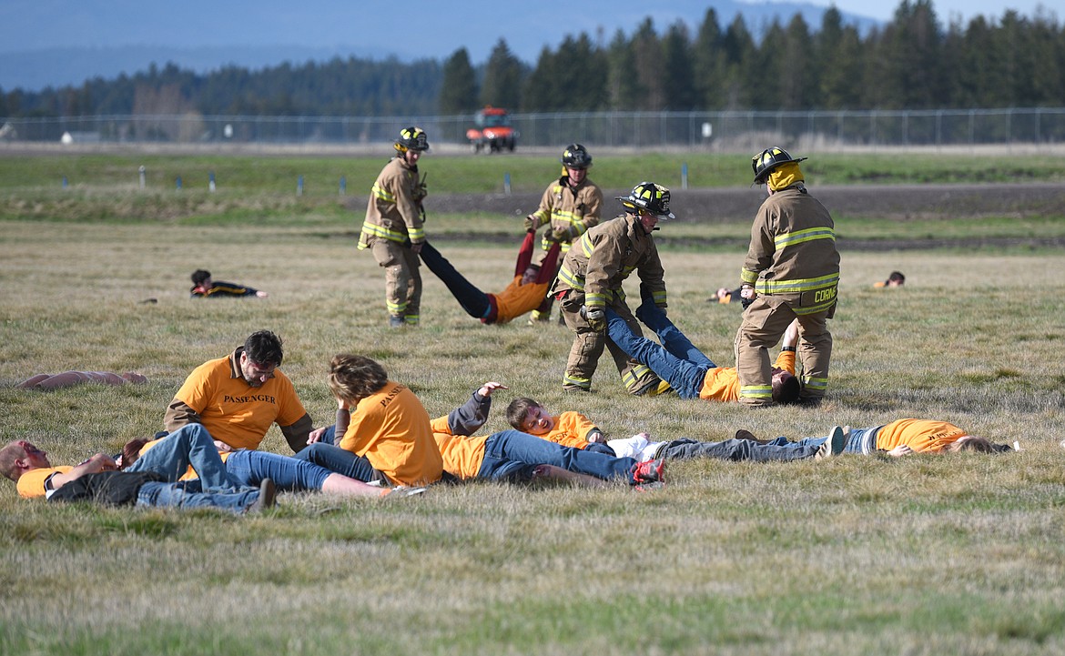 Firefighters transport injured passengers during an airport emergency simulation.