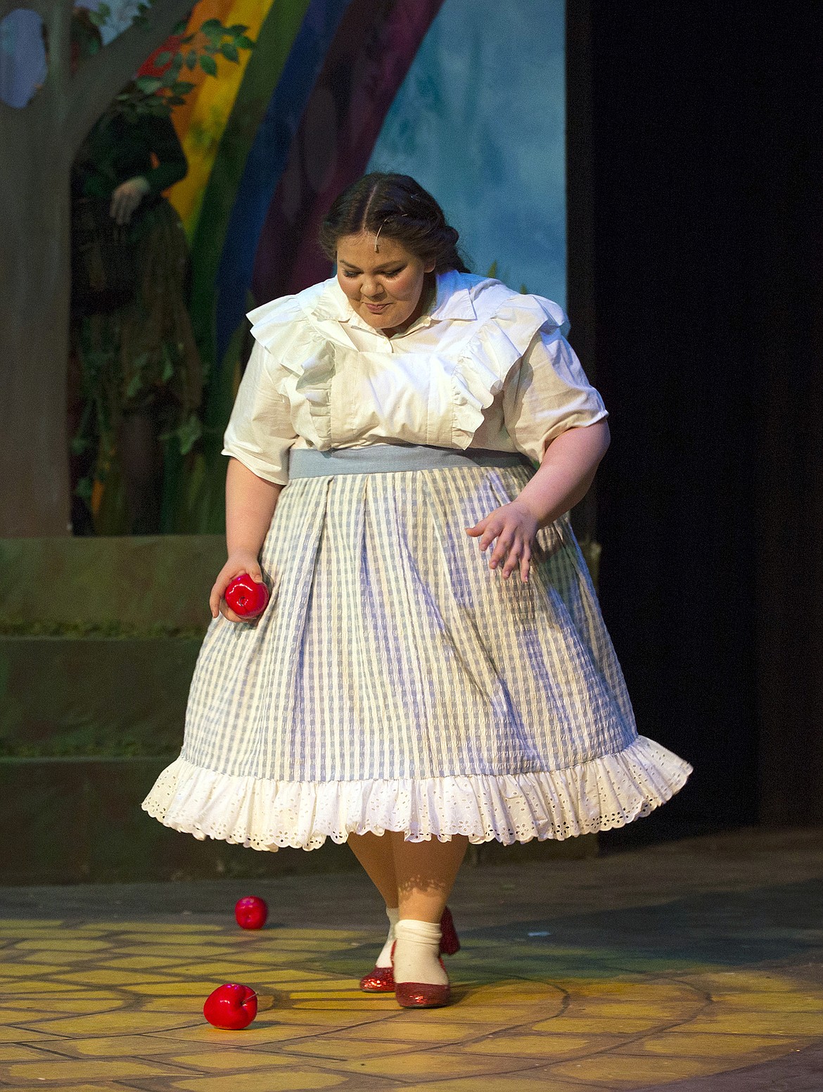 LISA JAMES/PressDorothy, played by Hannah Verdi, collects apples after tricking the talking trees into throwing them at her during Coeur d'Alene High School's dress rehearsal for  the Wizard of Oz. The production opened Thursday night and runs Friday and Saturday night, April 21, 22 and again 27-28-29.