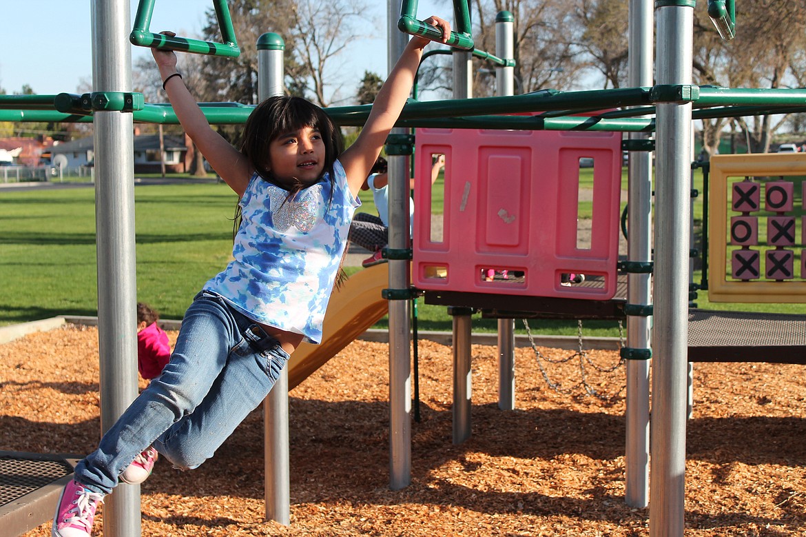 Charles H. Featherstone/Columbia Basin Herald
Seven-year-old Maryah swings on the monkey bars in Lions Park on Friday.