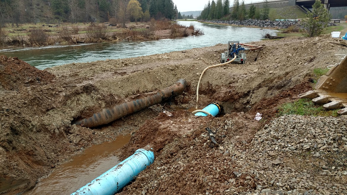 The new water main pipe where it connects to the old, existing system. You can also see a pump on the pile of dirt that is pumpoing seeping river water from the ditch back into the South Fork of the CDA River. Also note the old chunk of broken pipe laying near the ditch as well.