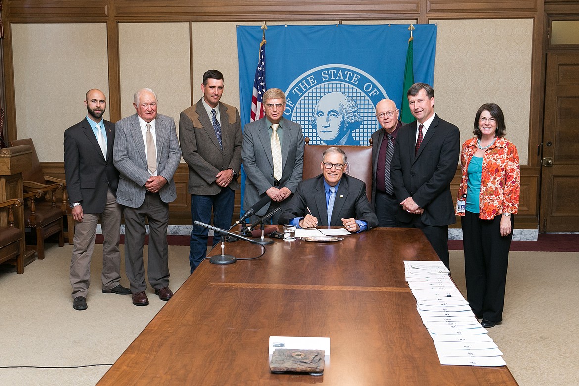 Cathy Potter/Courtesy Photo - Governor Inslee signs the Bill that transferred the title of the Royal Slope Railroad to the Port of Royal Slope. Pictured from left to right are Zak Kennedy (Grandson of lobbyist Jim Potts), Port Commissioner Frank Mianecki, Port Commissioner Davey Miller, Port Commissioner Alan Schrom, Governor Inslee, Port Lobbyist Jim Potts, Representative Matt Manweller and his assistant.