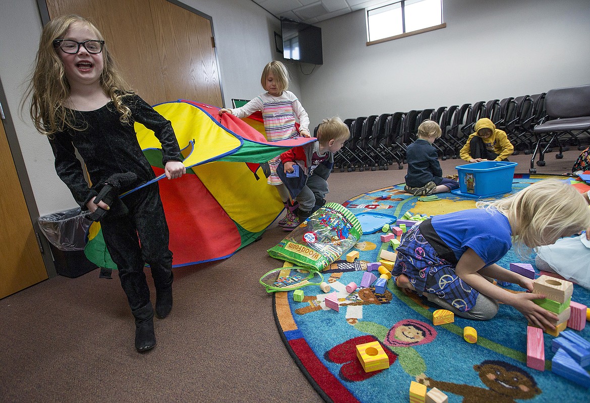 LISA JAMES/PressColette Collins, 4, in black, and Ally Kline, 7, carry a pop-up tent around the playroom of he Hayden Library as Elizabeth Clement, 6, right, plays with blocks following a French lesson on Friday, April 28. Many parents bring their children to the programs at area libraries for learning and social interaction.