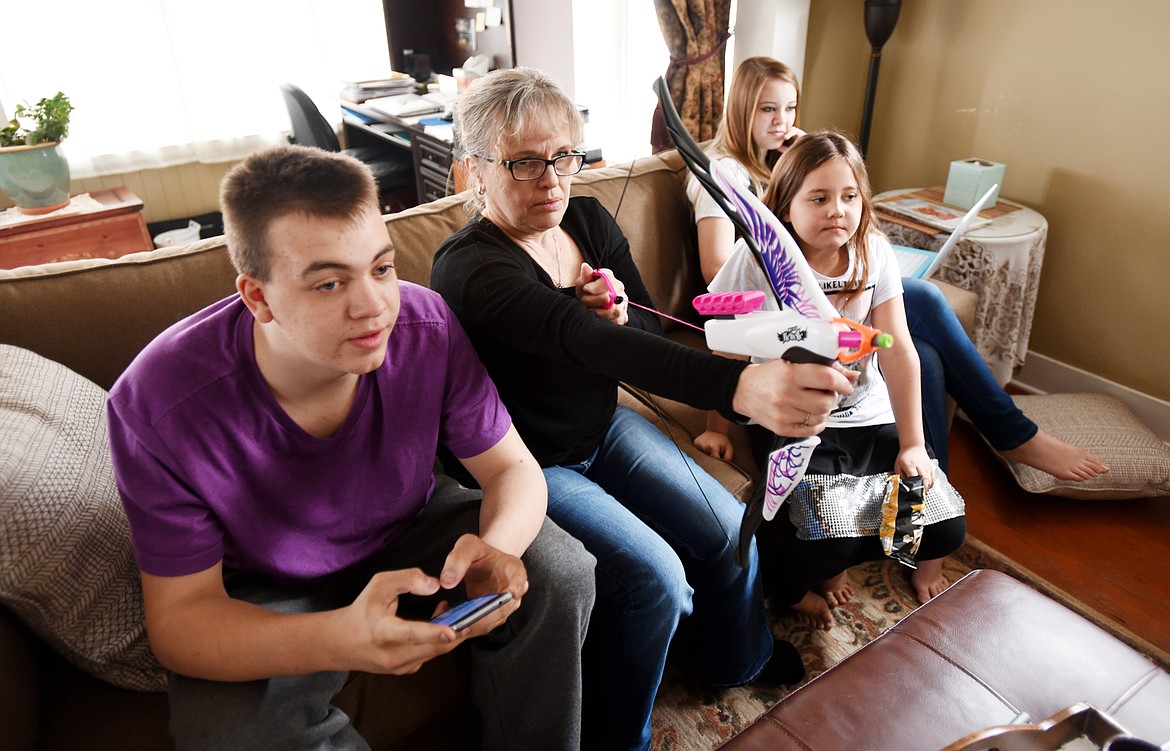 From left, Caleb Galloway, 17; Jacqueline Elm, their grandmother; Ella Kyger, 9; and Sury Galloway, 14, play games together in their living room after school on April 13 in Kalispell. (Brenda Ahearn/Daily Inter Lake)