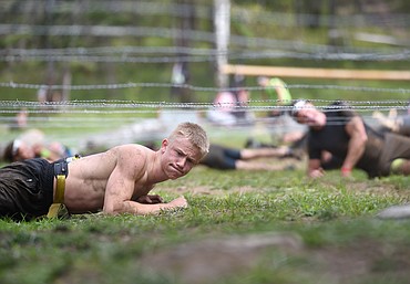 A competitor crawls under barb wire near the finish line of the Montana Spartan Race Beast at Averill's Flathead Lake Lodge near Bigfork on Saturday. (Aaric Bryan/Daily Inter Lake)