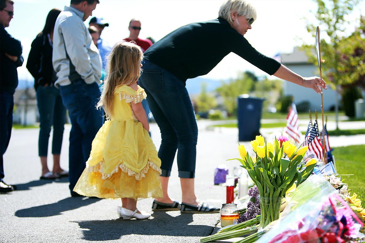 KRISTEN McPEEK/Press file
Debra Draeger straightens a photo of Sgt. Greg Moore displayed along with other memorial items May 6, 2015 on Wilbur Avenue in Coeur d&#146;Alene. Moore was shot at the location in the early morning hours of May 5, 2015 and later died.