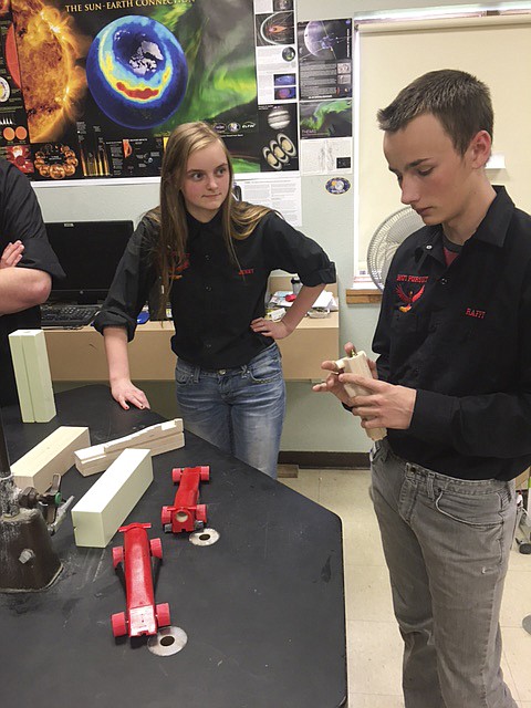 HOT PURSUIT Design Engineer Raferdy Samson, right, spins the wheels on his model racecar while Team Manager Jenny Scrivner looks on.