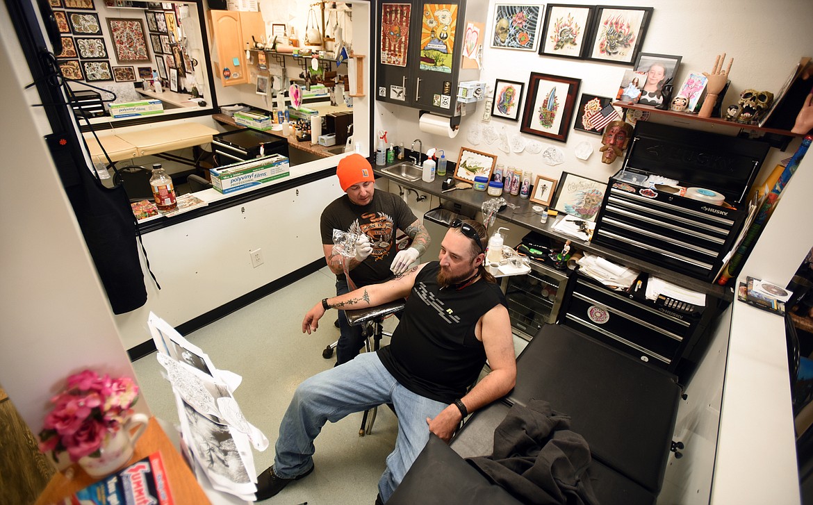Cody Swigert works on a tattoo for Louis Tedrick of Kalispell on May 8, at the Temple Decor in Kalispell.(Brenda Ahearn/Daily Inter Lake)