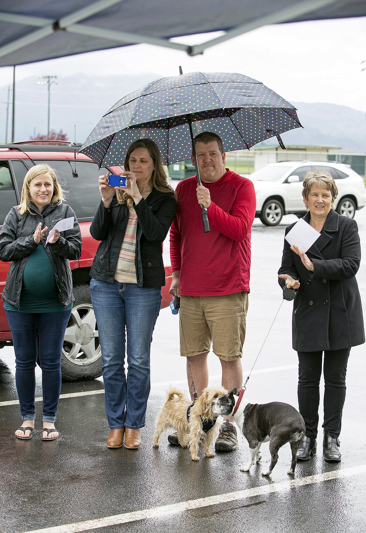 From left: Lauren Bierman, Shawn and Bill Langenderfer, and Lisa Troxel keep dry as their dogs greet each other during the ribbon-cutting ceremony of Hayden&#146;s first dog park, Pawfoot Park, on Friday.