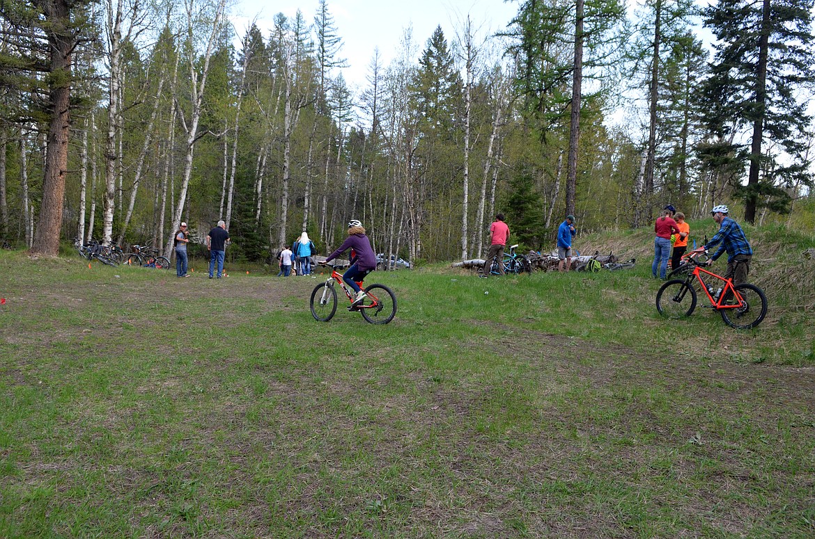 Folks ride and walk through the area that will become the parking lot on Reservoir Road for the Lower Haskill Trailhead for the Whitefish Trail following the gorund breaking ceremony last week. (Heidi Desch/Whitefish Pilot)