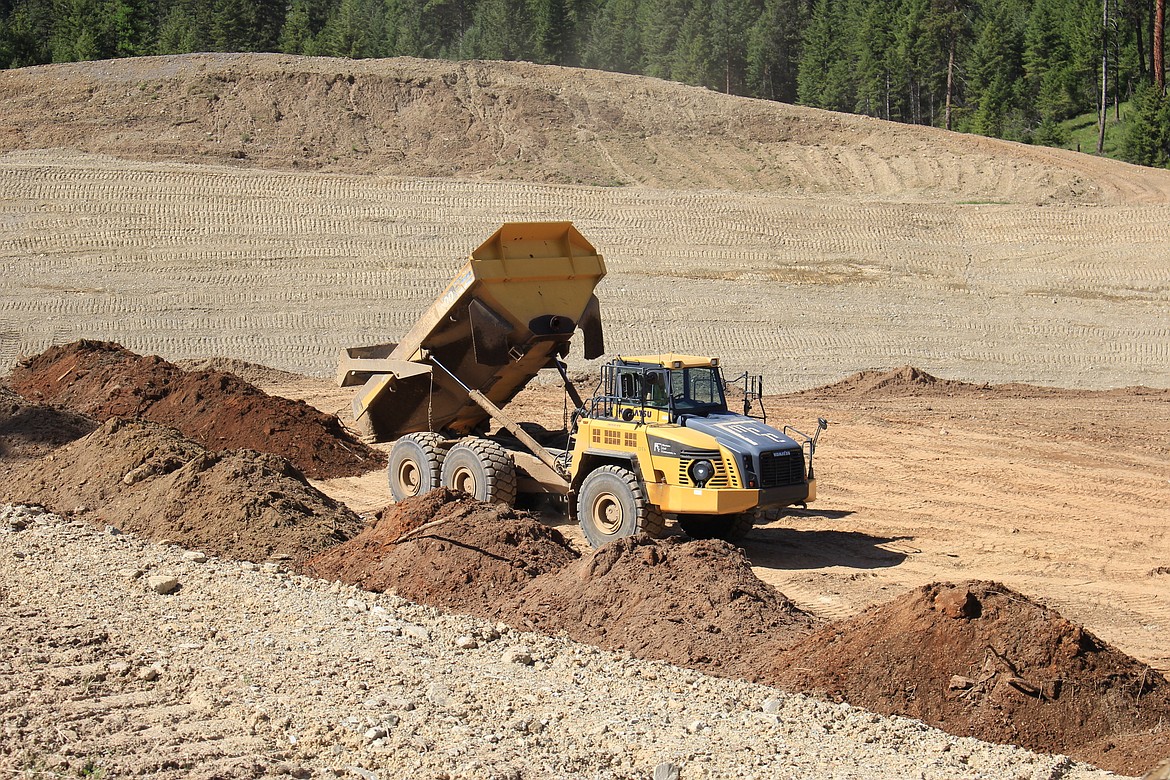 Contaminated mine tailings are hauled from the old mine to the repository where it will be covered with gravel and soil. Highly contaminated tailings appear red and orange in color. (Kathleen Woodford/Mineral Independent).