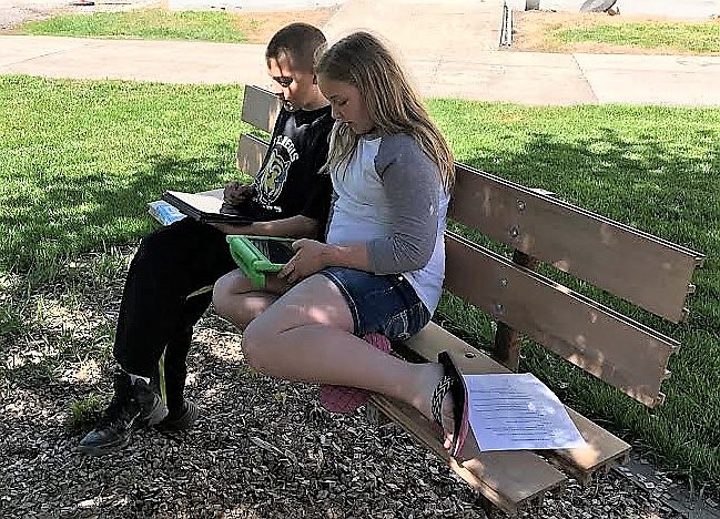 St. Regis 6th graders Gyme Kelly and Brook Filek work on their class backpack program to provide supplies to students in need. (Photo courtesy of Tim Yeager).