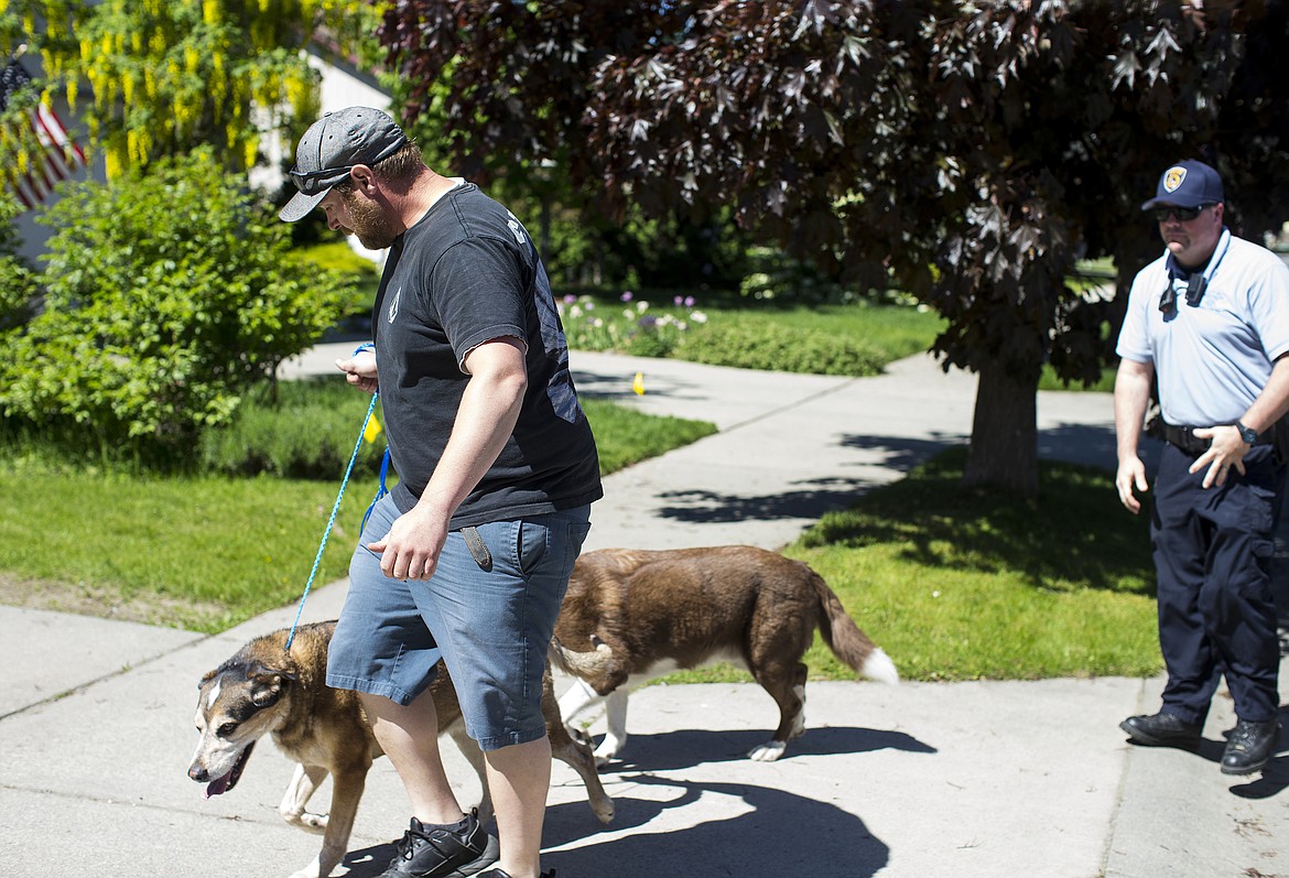 LOREN BENOIT/PressJon Beamesderfer, right, with Coeur d'Alene Police Animal Control successfully returns lost dogs Odie and Mojo to Matt Morgan after the dogs slipped out of the front door and wandered local neighborhoods Friday morning.